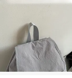 Detail of grey nylon backpack with durable woven handle and white MUTING embroidery