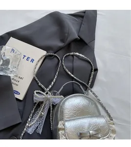 Detail of silver metallic mini backpack with white lace edges and pearl chain strap