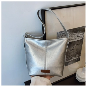 Detail shot of silver bucket bag with grain texture and brand logo tag