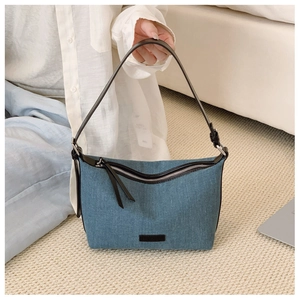 Dettaglio della borsa hobo in denim blu con tracolla in pelle nera e fibbia argento