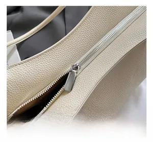 Close-up of smooth silver zipper hardware on a beige litchi grain leather tote bag