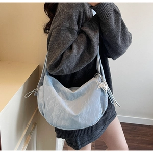 Detail of light blue dumpling bag with wrinkled texture and metal butterfly charm