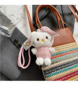 Dettaglio di un ciondolo peluche Hello Kitty con vestito in tweed su borsa di paglia