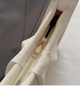 Détail du zip en métal doré lisse et du cuir plissé blanc cassé du sac seau
