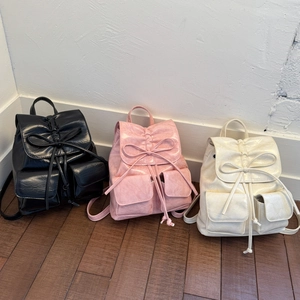 Detailed comparison of three backpacks in black, pink, and cream with bow drawstrings