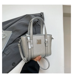 Dettaglio di una borsa tote argento metallizzato con placca quadrata e tracolla sottile