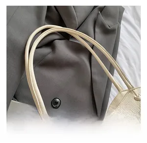 Detail of soft leather tote bag handle with checkered ribbon and mini hat charm