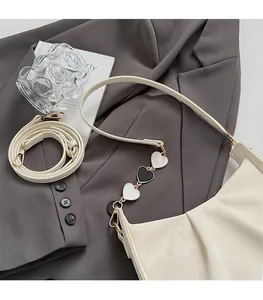 Détail du sac plissé crème avec chaîne décorative à cœurs noirs et blancs en métal