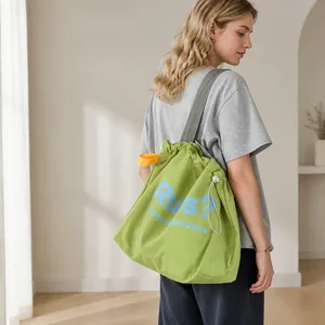 Detail of green drawstring tote bag showing crinkled nylon texture and printed lettering