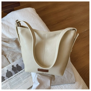 Detailed view of cream bucket bag with lychee texture and brand leather label