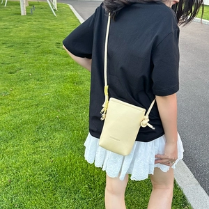 Détail du sac bandoulière en cuir grainé jaune clair avec logo SUNWOMEN embossé