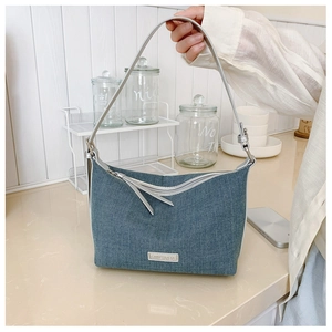 Dettaglio borsa a tracolla in denim blu con finiture argentate su un piano cucina