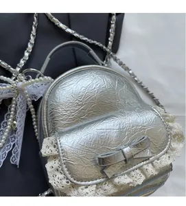Detail of silver crushed texture fabric with lace trim and bow on a mini backpack