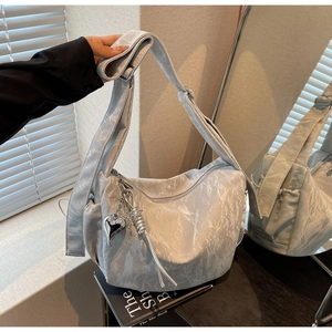 Close-up of light grey dumpling bag with pleated texture and silver heart pendant