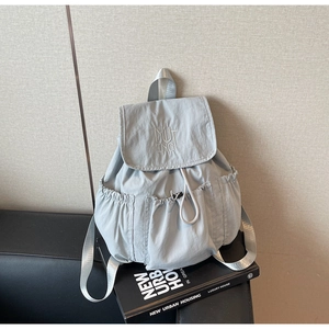 Detail view of light blue nylon backpack with drawstring pockets and MUTING embroidery