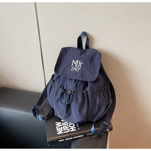 Detail eines dunkelblauen Nylon-Rucksacks mit Kordelzug und MUTING-Stickerei am Deckel