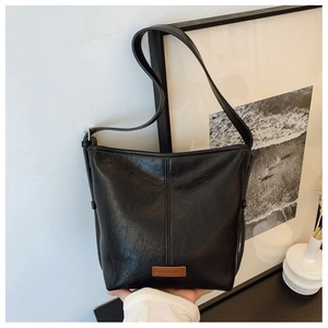 Detail of classic black bucket bag with refined stitching and brand logo patch