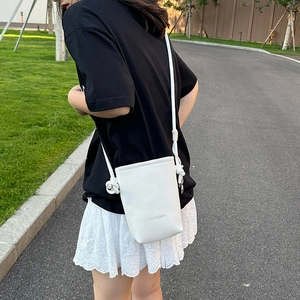 Détail du sac seau blanc en cuir grainé avec une bandoulière à nœuds tissés élégante