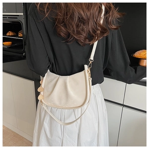 Sac seau plissé beige chic avec breloque en forme de cœur dans un décor de style de vie