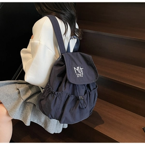 Detail view of navy nylon backpack featuring white embroidery logo and drawstring closure