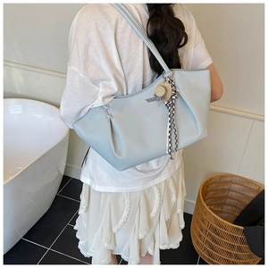 Detail of light blue tote bag featuring lychee texture leather and mini hat charm