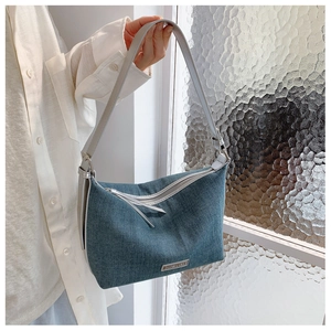 Dettaglio della borsa hobo in denim blu con placca logo in metallo e tracolla grigio argento