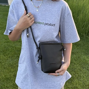 Sac à bandoulière minimaliste noir en cuir sur mannequin sur herbe verte