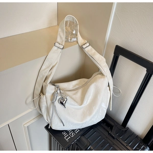 Detail of off-white large capacity dumpling bag with heart pendant and adjustable strap