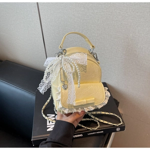 Gros plan du mini sac à dos en cuir plissé jaune avec dentelle et chaîne de perles