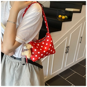 Detail of red polka dot shoulder bag with cute teddy bear charm on silky fabric