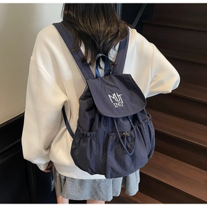 Detail of navy nylon backpack with MUTING embroidery and drawstring closure