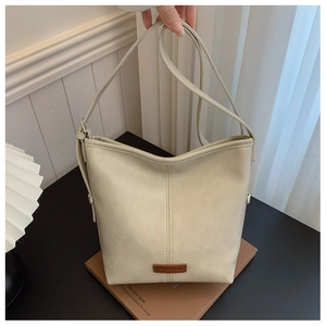 Detail of cream bucket bag showing lychee pattern faux leather and dark brown logo tag