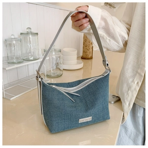 Dettaglio della borsa hobo in denim blu con finiture metalliche argentate e placca logo