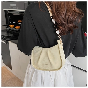 Détail du sac sous le bras en daim crème avec charme de bandoulière en forme de cœur