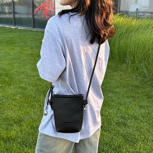 Détail du petit sac seau noir pour téléphone avec texture grainée et logo discret