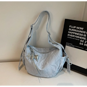 Detail of light blue nylon dumpling bag featuring silver butterfly and heart charms