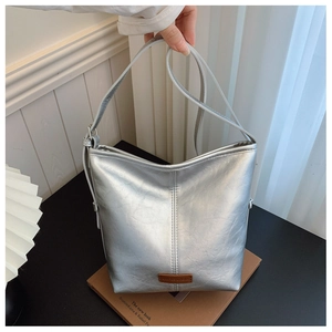 Detail of silver bucket bag with metallic texture and brown leather label accent