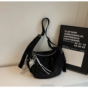 Detail of black pleated crossbody bag featuring silver zipper and butterfly charm detail