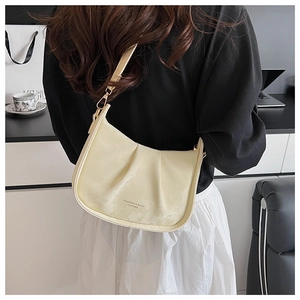 Gros plan du sac à bandoulière plissé en cuir crème avec détails métalliques de mode