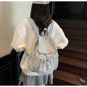 Detail of light gray nylon backpack with MUTING embroidery and drawstring closure