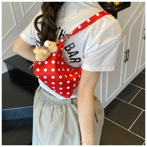 Detail einer roten Schultertasche mit weißen Punkten und beige Teddybären-Anhänger