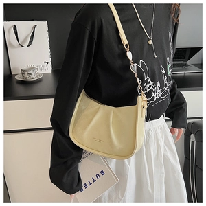 Détail d'un sac hobo plissé beige crème avec une boucle décorative en cœur