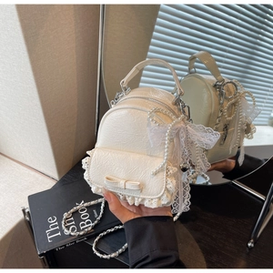 Gros plan du mini sac à dos crème avec bordure en dentelle et détails de nœuds en perles