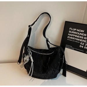 Detail of black nylon hobo bag featuring a silver butterfly heart charm and zip closure
