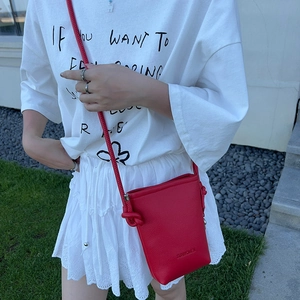 Vue détaillée d'un mini sac bandoulière en cuir rouge avec bandoulière à nœuds