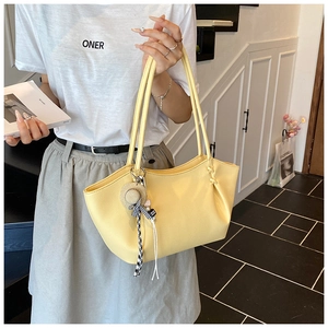Detail view of yellow lychee textured tote bag with mini straw hat and ribbon charm