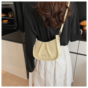Détail du sac demi-lune plissé crème avec bandoulière et texte en cuir embossé