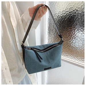 Dettaglio della borsa in denim blu con tracolla in pelle nera e finiture metalliche