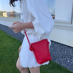 Photo extérieure d'un mini sac bandoulière rouge avec grain de cuir et nœud décoratif