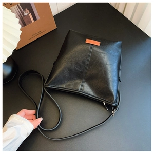 Top view of black textured leather bucket bag with brown leather label and zipper detail